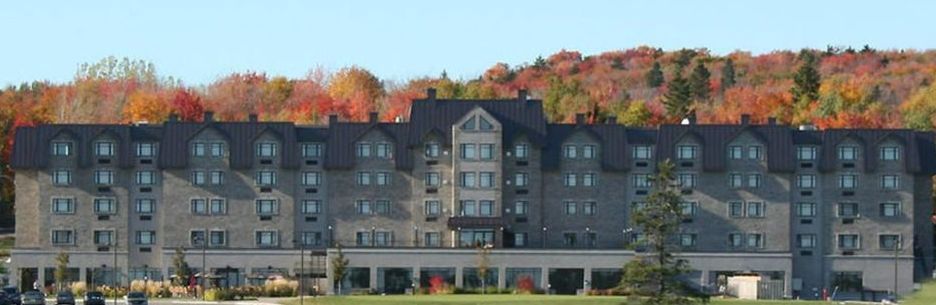 Un grand bâtiment avec beaucoup de fenêtres est entouré d'arbres.