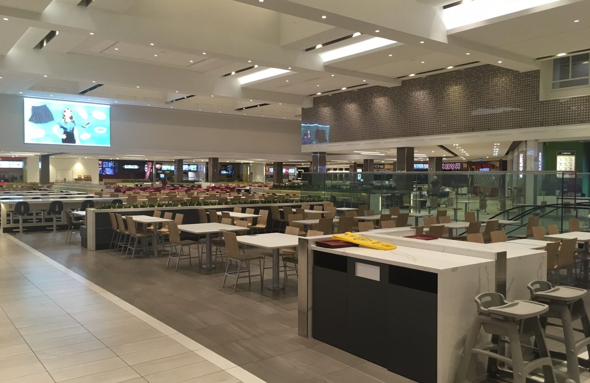 Une aire de restauration vide dans un centre commercial avec des tables et des chaises.