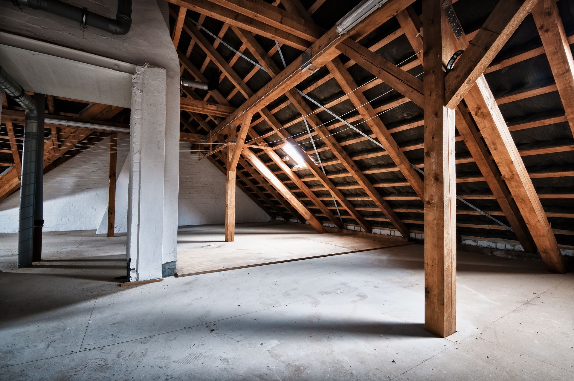 An empty attic with wooden beams and a roof.