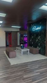 A room with a table and benches in it and a neon sign on the wall.
