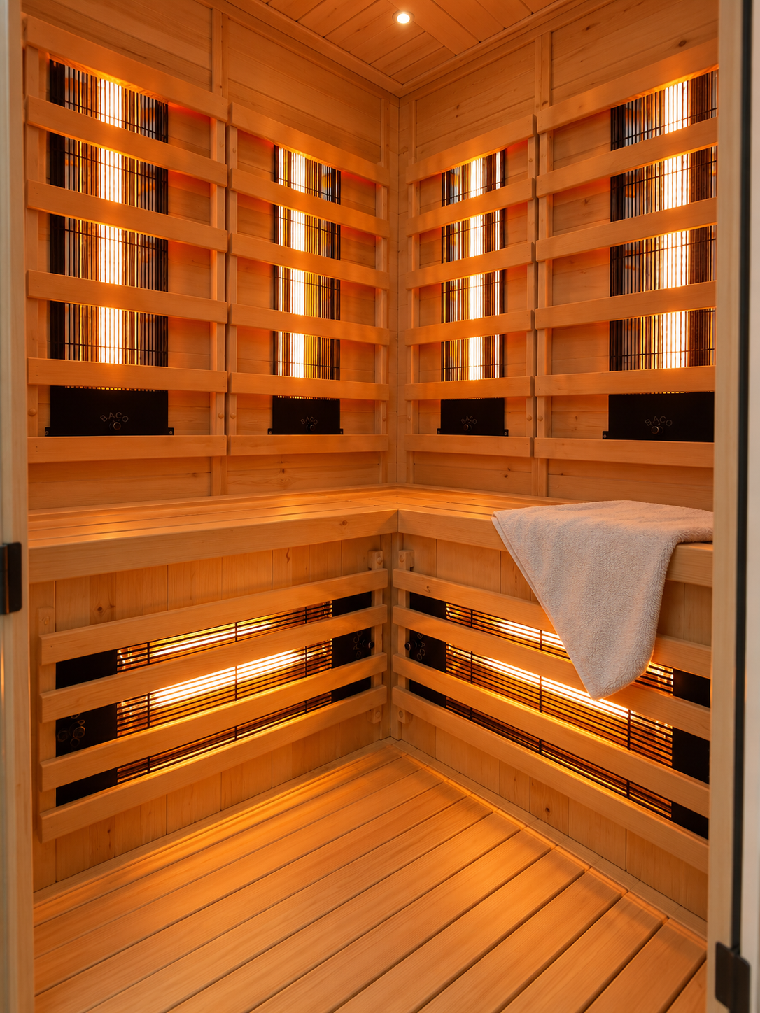 Sauna met houten lambrisering, sfeervolle verlichting, zitbanken en handdoeken die aan de zijkant hangen.