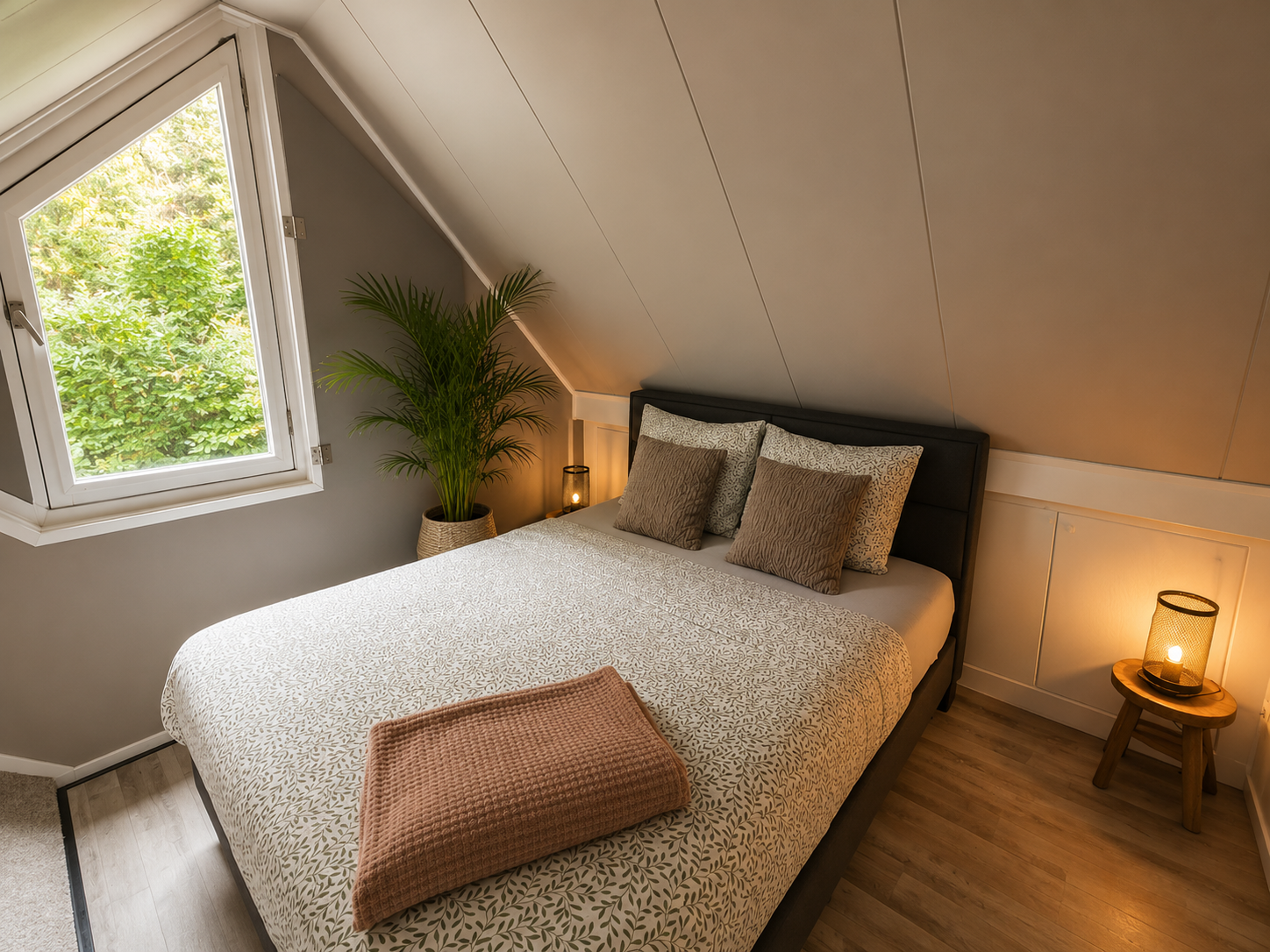 Gezellige zolderkamer met een bed, nachtkastjes, warm lamplicht en een dakraam.