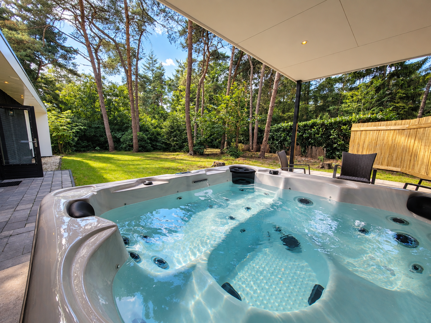 Een jacuzzi in de achtertuin, onder een overkapping, borrelt zachtjes naast een groen gazon en bomen.