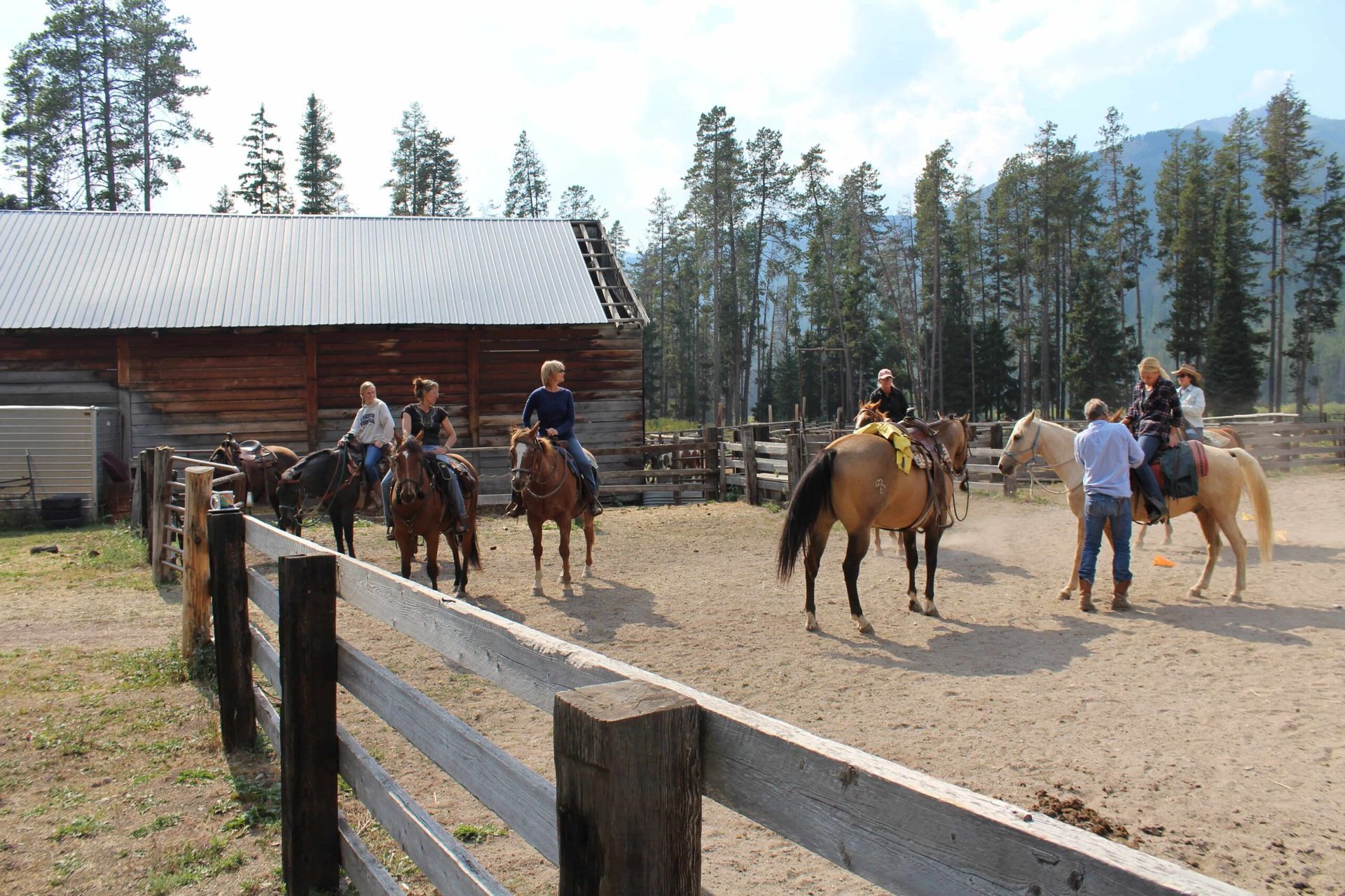 A group of people riding horses in a fenced in area