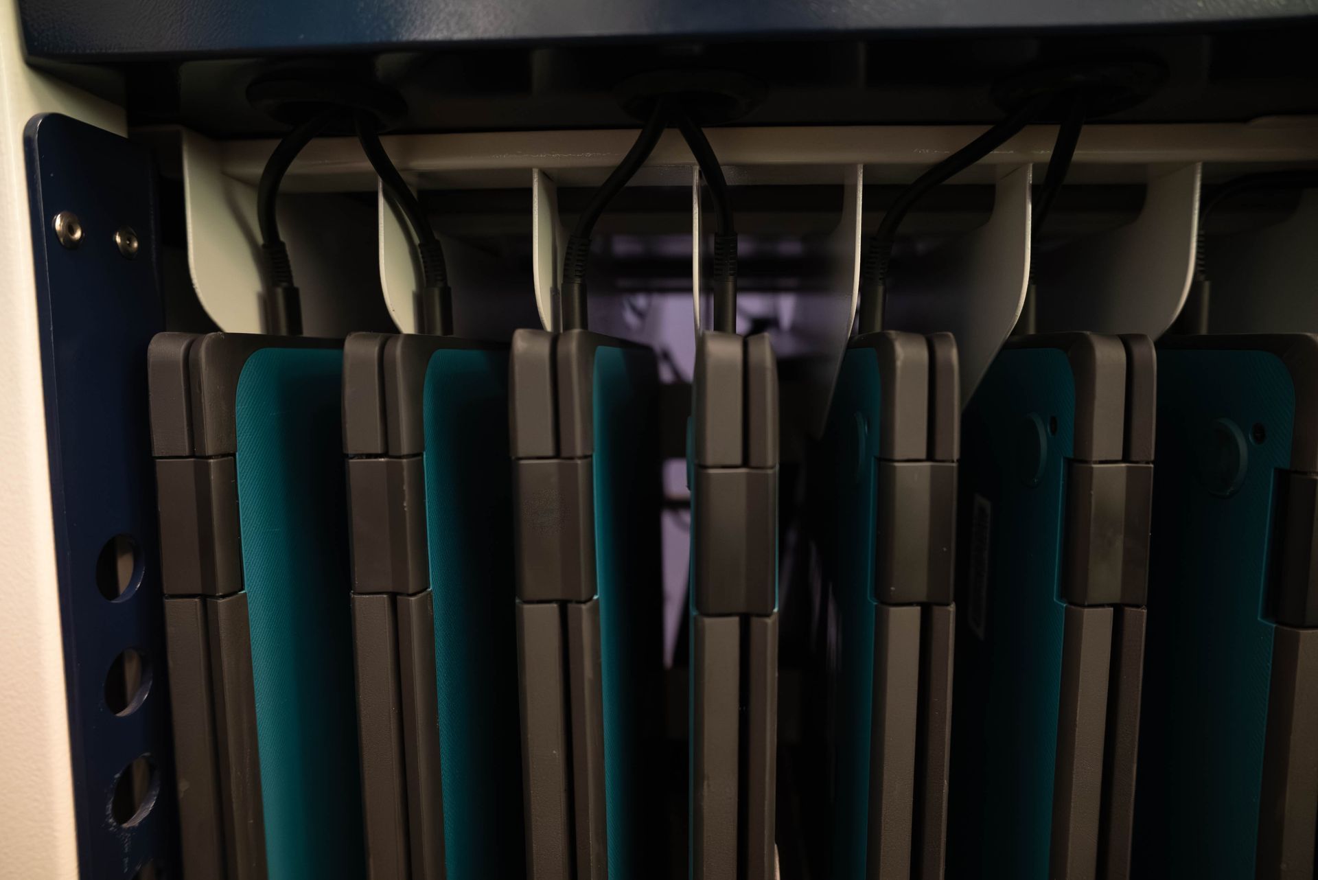 Close-up of folded teal and black chairs stacked in a storage rack