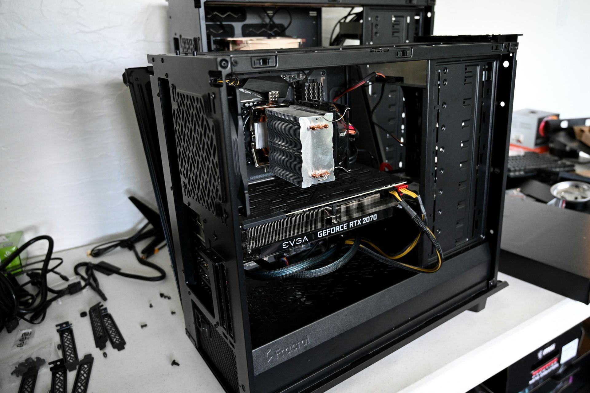 Open black PC case with visible internal components on a desk in a workshop.
