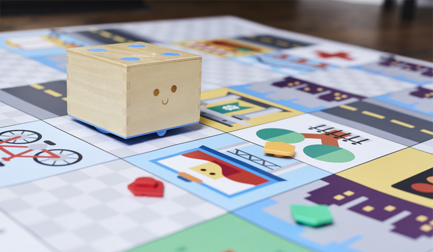 Small wooden toy cube with a face on a colorful board game mat with roads and icons
