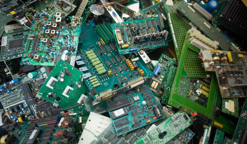 Piles of green printed circuit boards and electronic components scattered together.