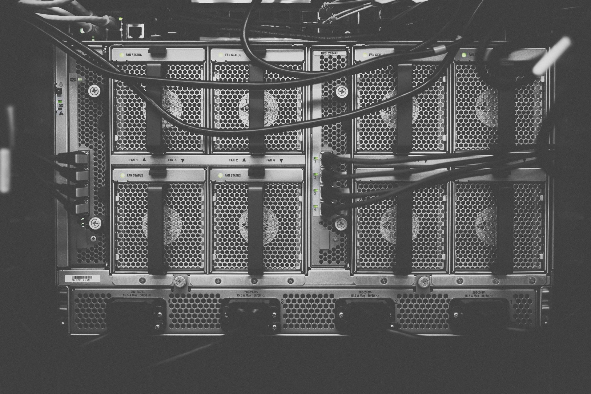 Black-and-white industrial server rack with cables and metal mesh panels in a dim room
