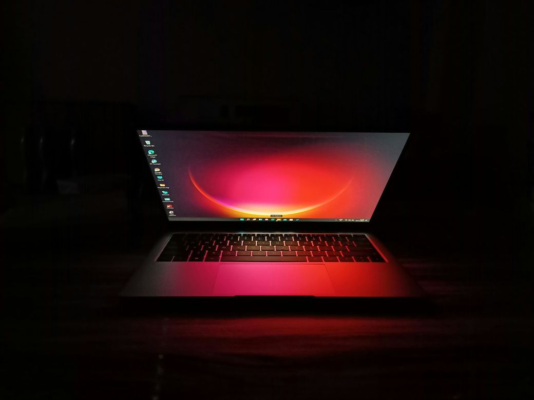 Laptop with glowing red screen on a dark background, centered and open