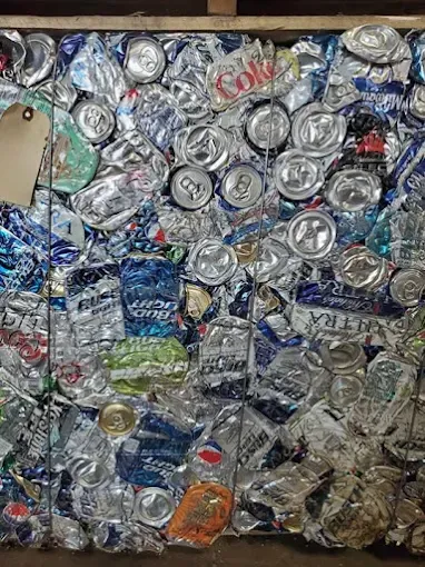 A compressed bale of various crushed aluminum beverage cans, tightly secured with wire.