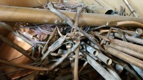 A pile of copper pipes and scrap metal, including various lengths, fittings, and connectors.