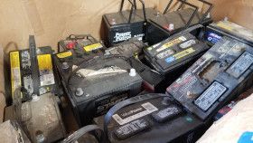 A collection of used lead-acid automotive batteries stacked inside a cardboard box.