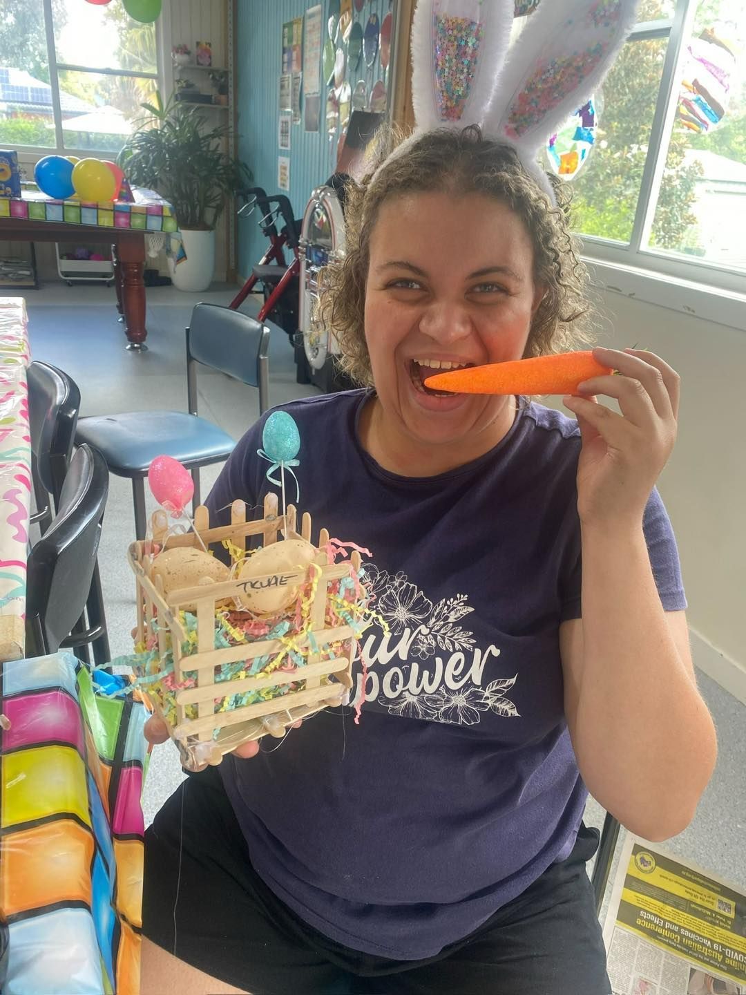 Centre based fun activities. A woman wearing bunny ears is eating a carrot.