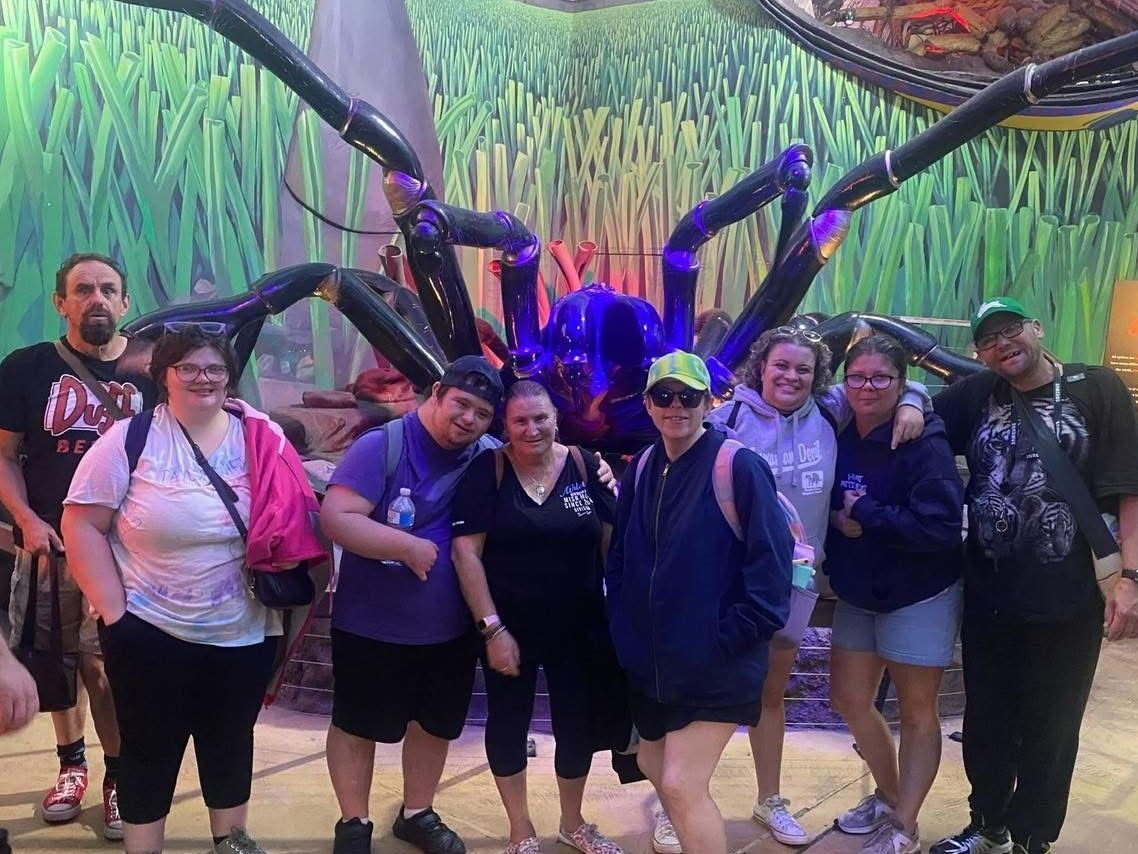Social and Community group outing. A group of people are posing for a picture in front of a giant inflatable spider.