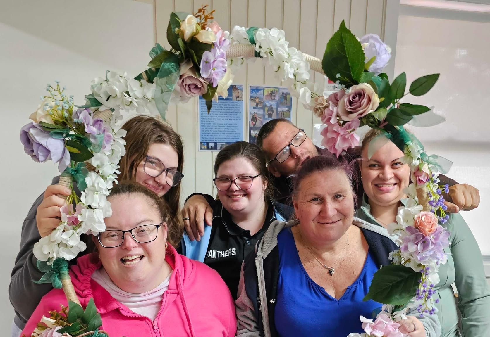 A group of people are posing for a picture with flowers on their heads.