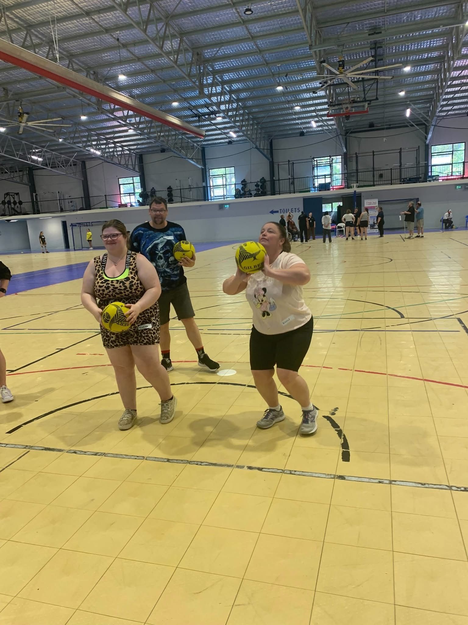 A group of people are playing basketball in a gym.