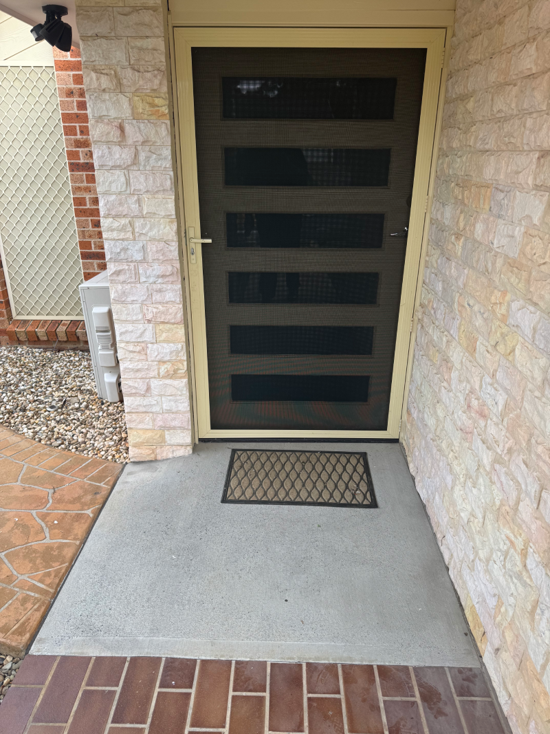 A brick wall with a door and a mat in front of it.