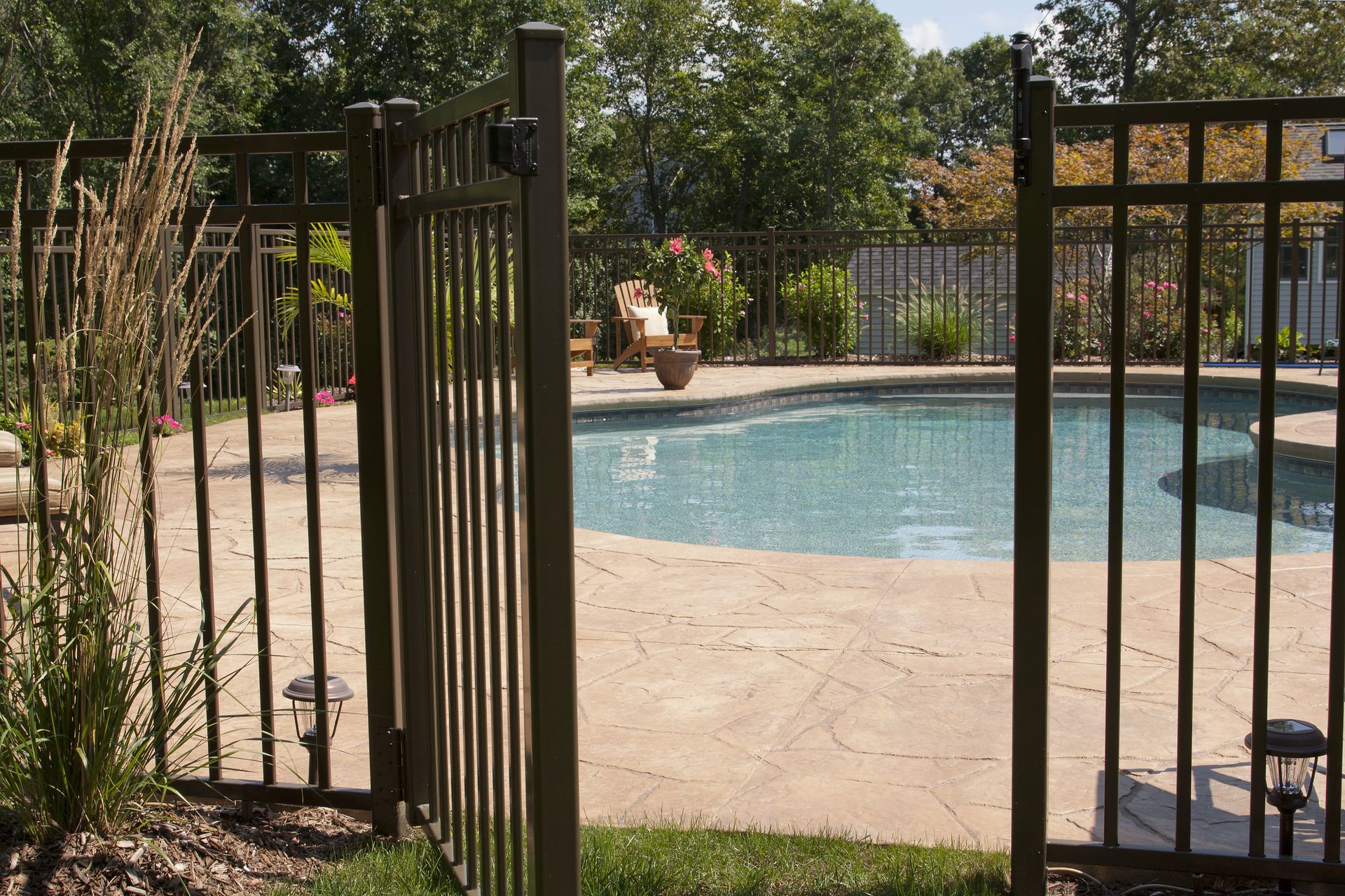 a fence surrounds a swimming pool in a backyard with stamped concrete