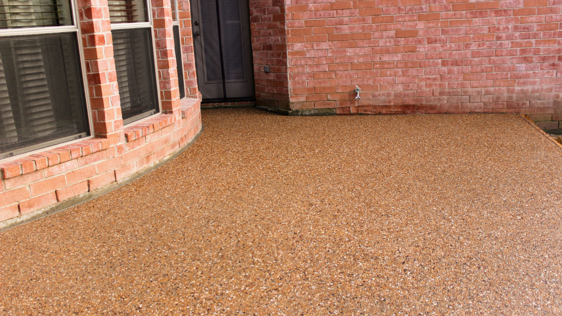 a brick house with an exposed aggregate concrete driveway in front of it 
