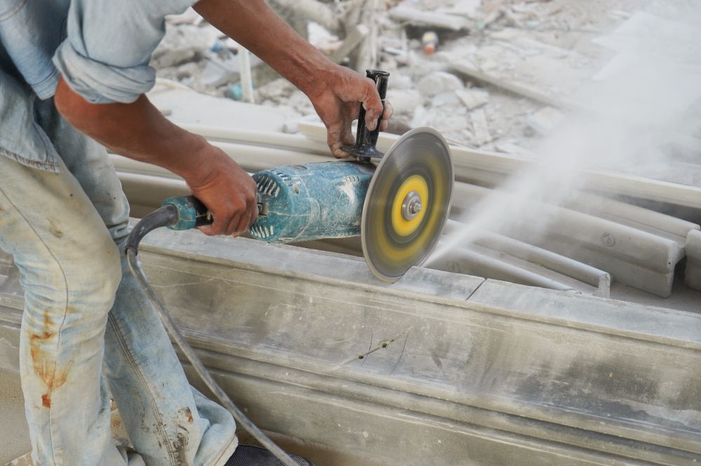 A Man Is Cutting A Piece Of Concrete With A Grinder — Pro Cut N Core In Mareeba, QLD