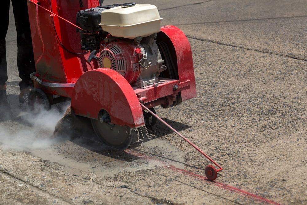 A Person Is Using A Concrete Saw To Cut A Line On The Ground — Pro Cut N Core In Cairns, QLD