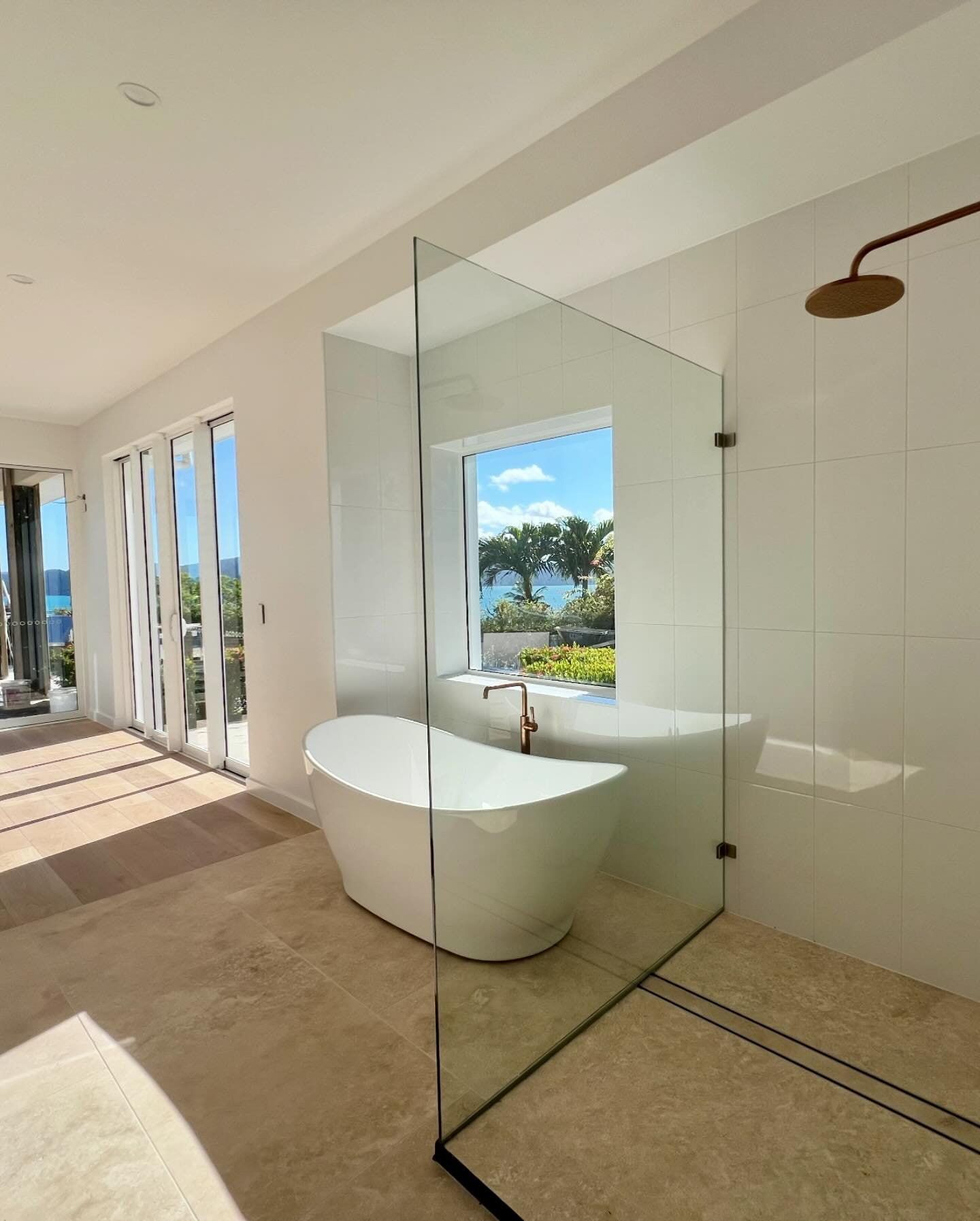 A Bathroom With a Bathtub and a Shower With a View of the Ocean โ Coral Coast Building & Management in Cannon Valley, QLD