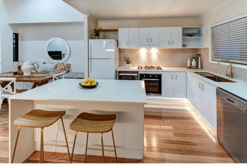 A Kitchen With White Cabinets and Wooden Floors — Coral Coast Building & Management in Cannon Valley, QLD