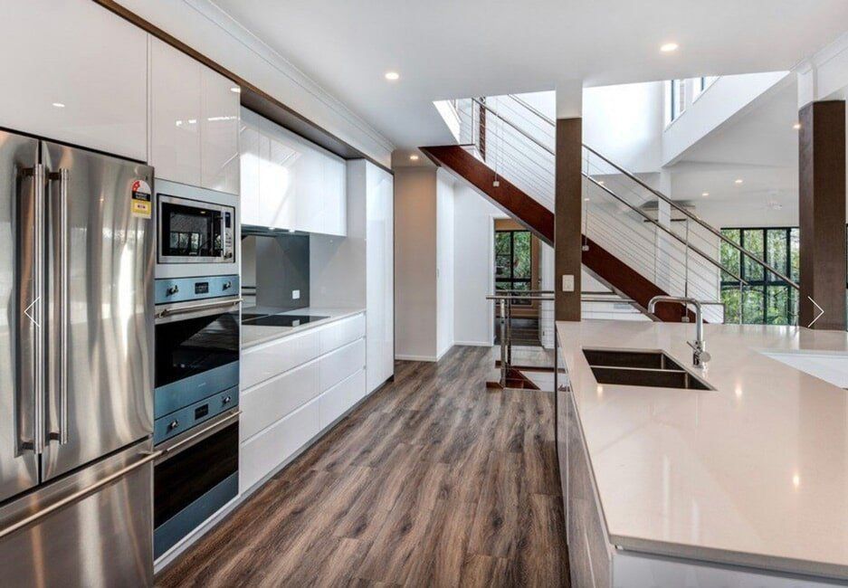 A Kitchen With Stainless Steel Appliances and a Staircase in the Background — Coral Coast Building & Management in Cannon Valley, QLD