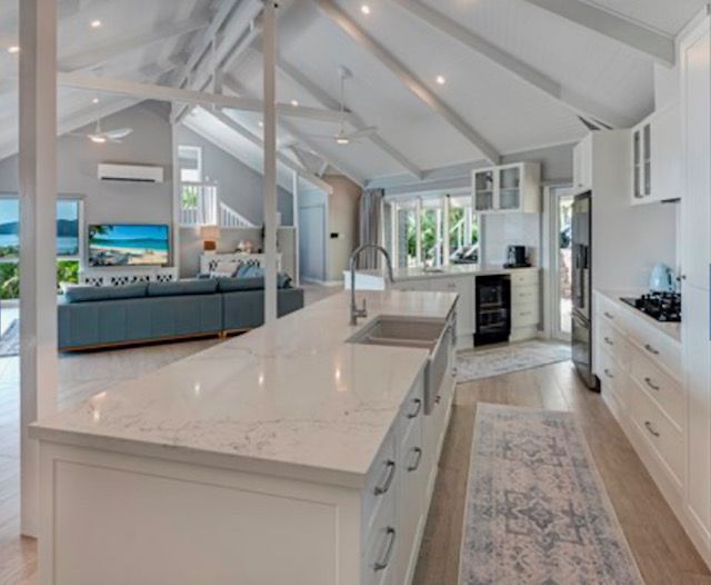 A Kitchen With White Cabinets and a Large Island in the Middle — Coral Coast Building & Management in Cannon Valley, QLD
