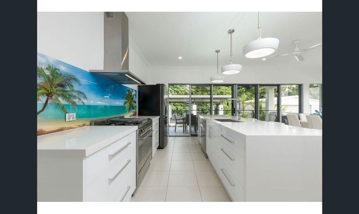A Kitchen With White Cabinets , Stainless Steel Appliances , and a Large Island — Coral Coast Building & Management in Cannon Valley, QLD