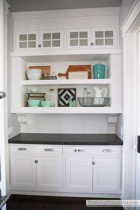 A Kitchen With White Cabinets and Shelves and a Black Counter Top — Coral Coast Building & Management in Cannon Valley, QLD