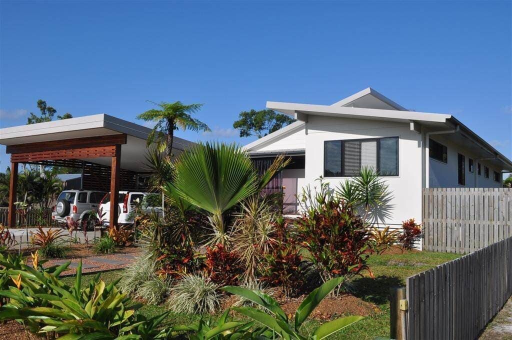 A White House With a Wooden Fence in Front of It — Coral Coast Building & Management in Cannon Valley, QLD