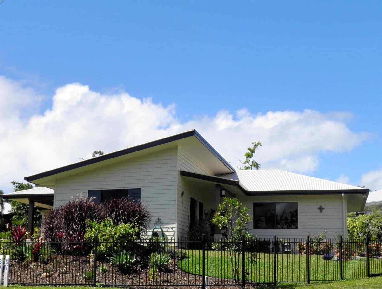 A White House With a Black Roof and a Fence in Front of It — Coral Coast Building & Management in Cannon Valley, QLD