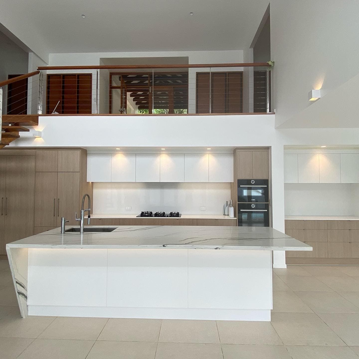 A Kitchen With White Cabinets and a Large Island — Coral Coast Building & Management in Cannon Valley, QLD