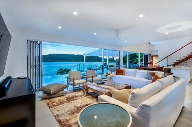 A Living Room With a Couch , Chairs , and a Table With a View of the Ocean — Coral Coast Building & Management in Cannon Valley, QLD