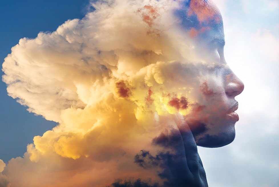 Una doble exposición del rostro de una mujer y las nubes.