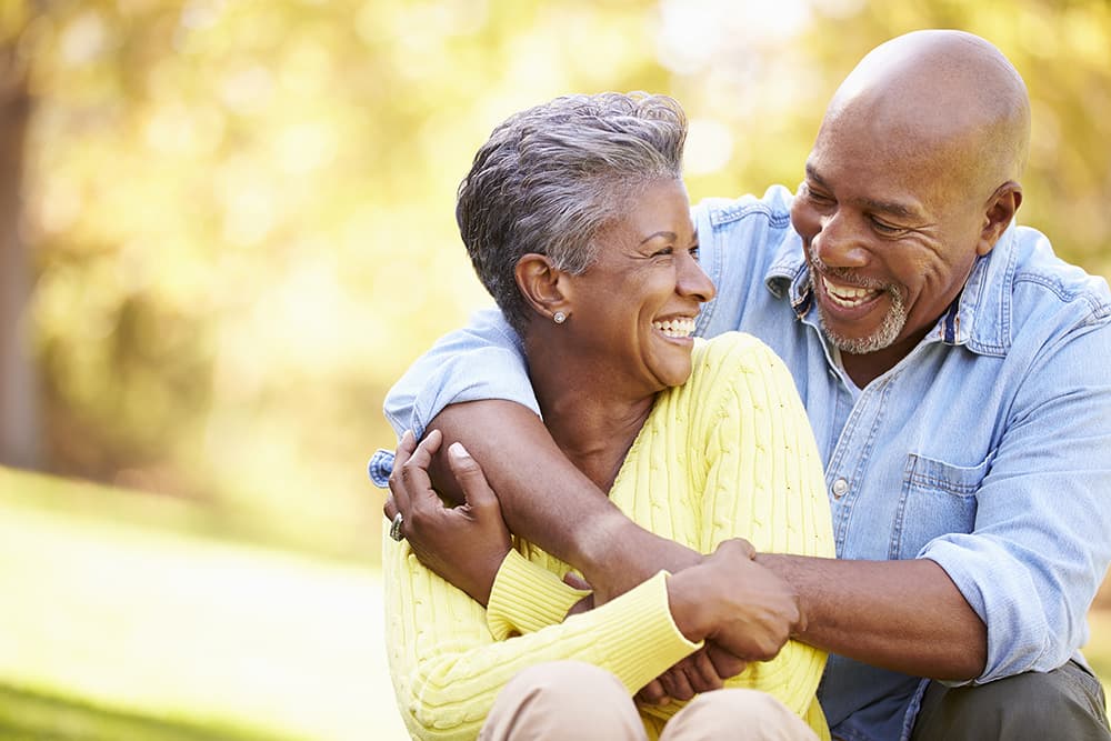 Two people smiling and hugging outdoors in a sunny park