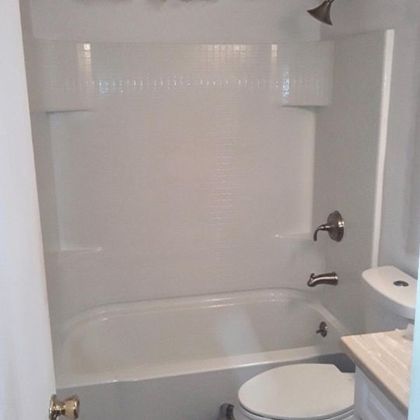 A bathroom with a tub , toilet and shower.