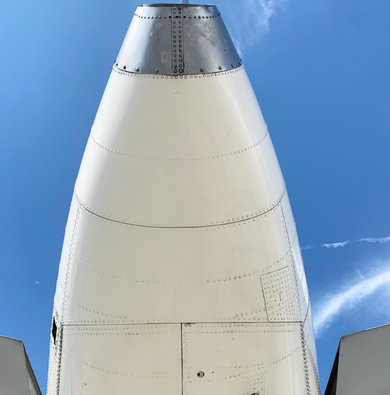 A white airplane with a silver cone on top of it