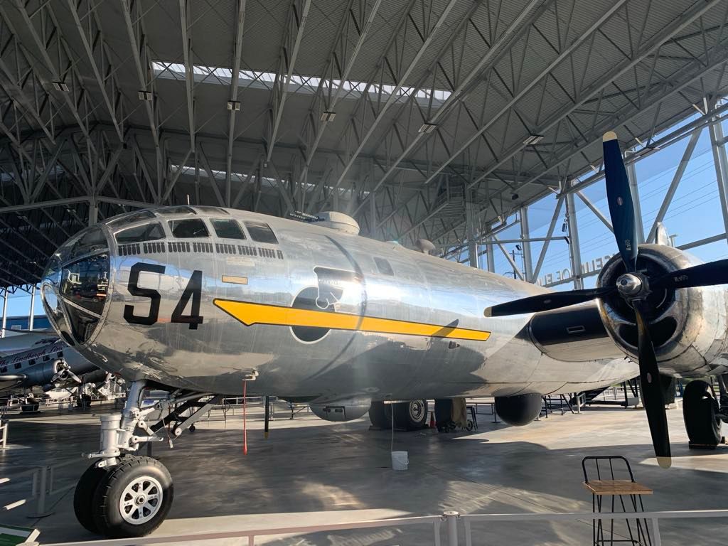 A large silver airplane with the number 54 on the side is parked in a hangar.