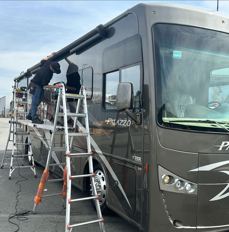 A man standing on a ladder next to a rv that says palazzo