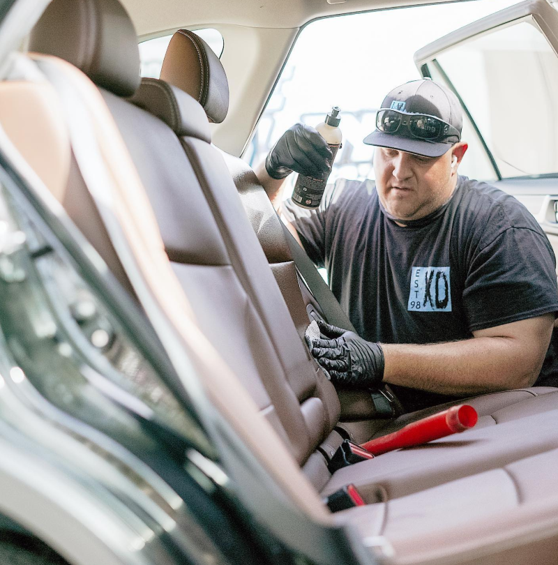 A man in a xd shirt is sitting in the back seat of a car