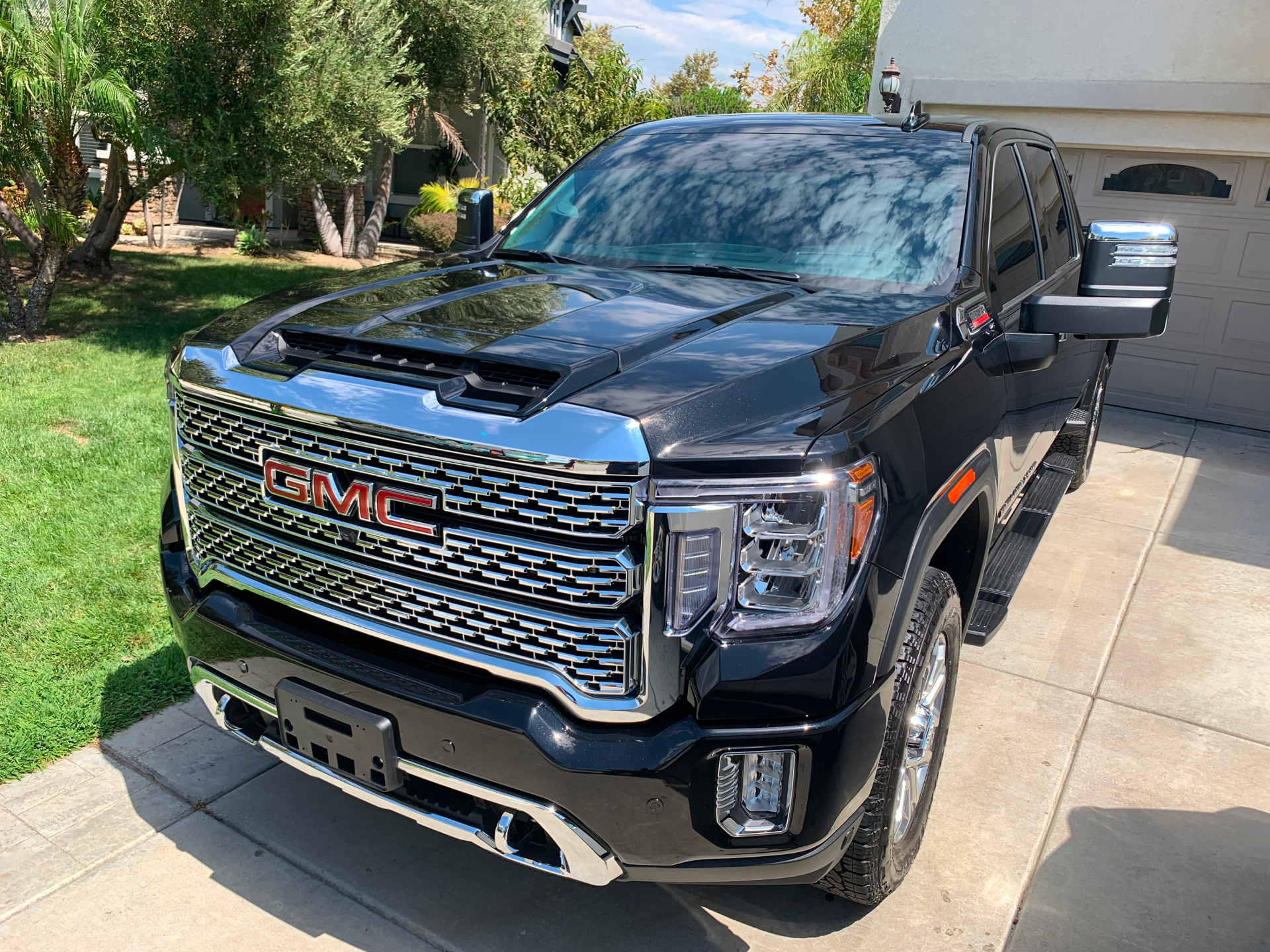 Black GMC pickup truck parked in a driveway beside a lawn and garage.
