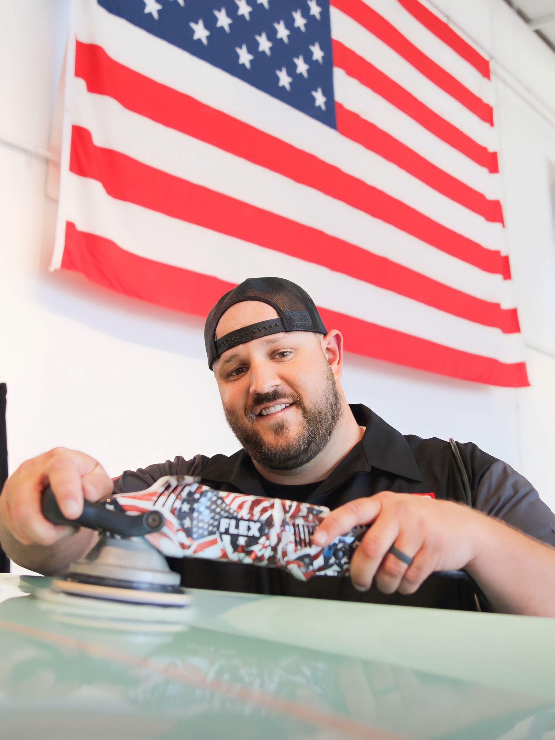 a man is polishing a skateboard in front of an american flag