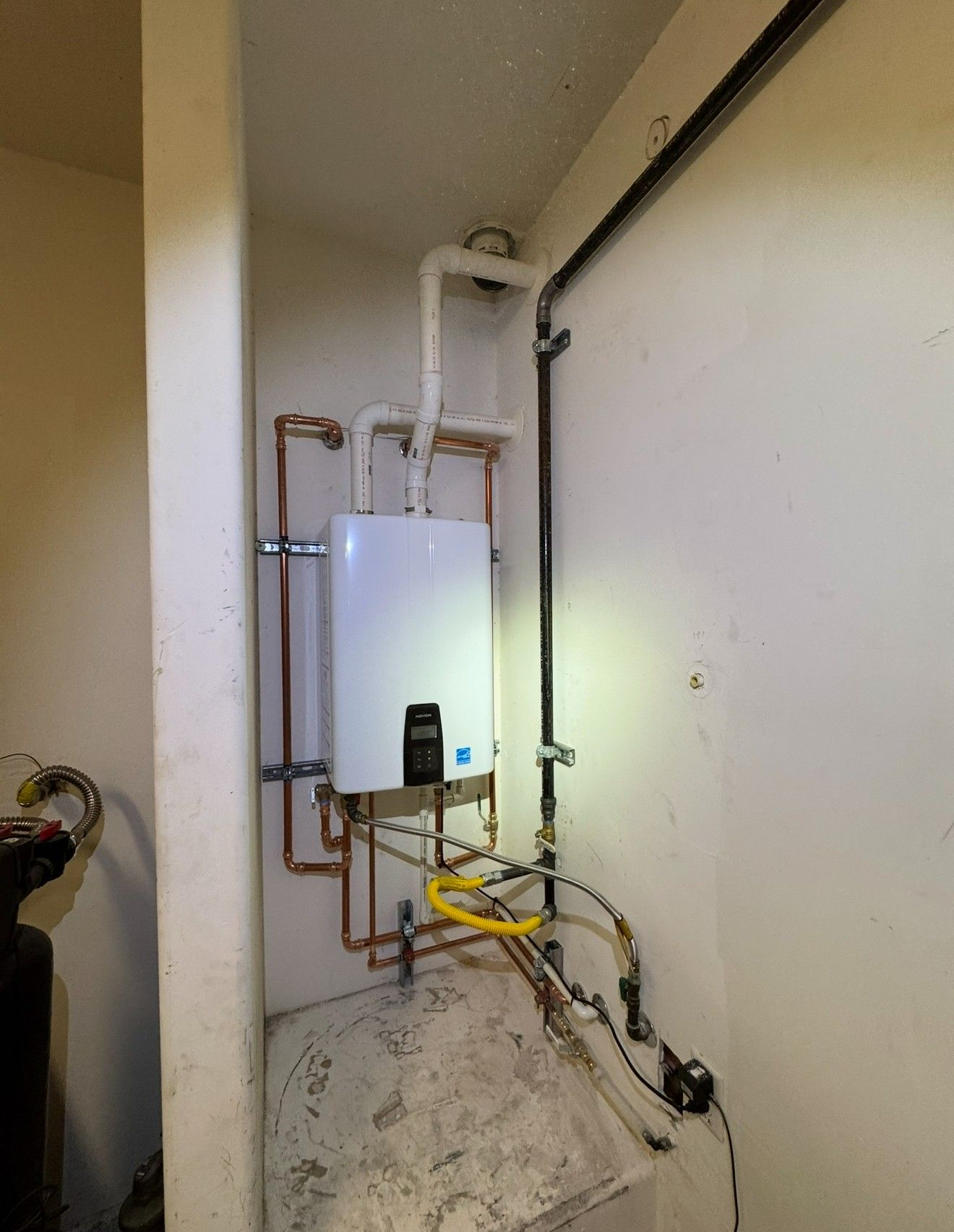 Wall-mounted boiler and exposed pipes in a utility closet