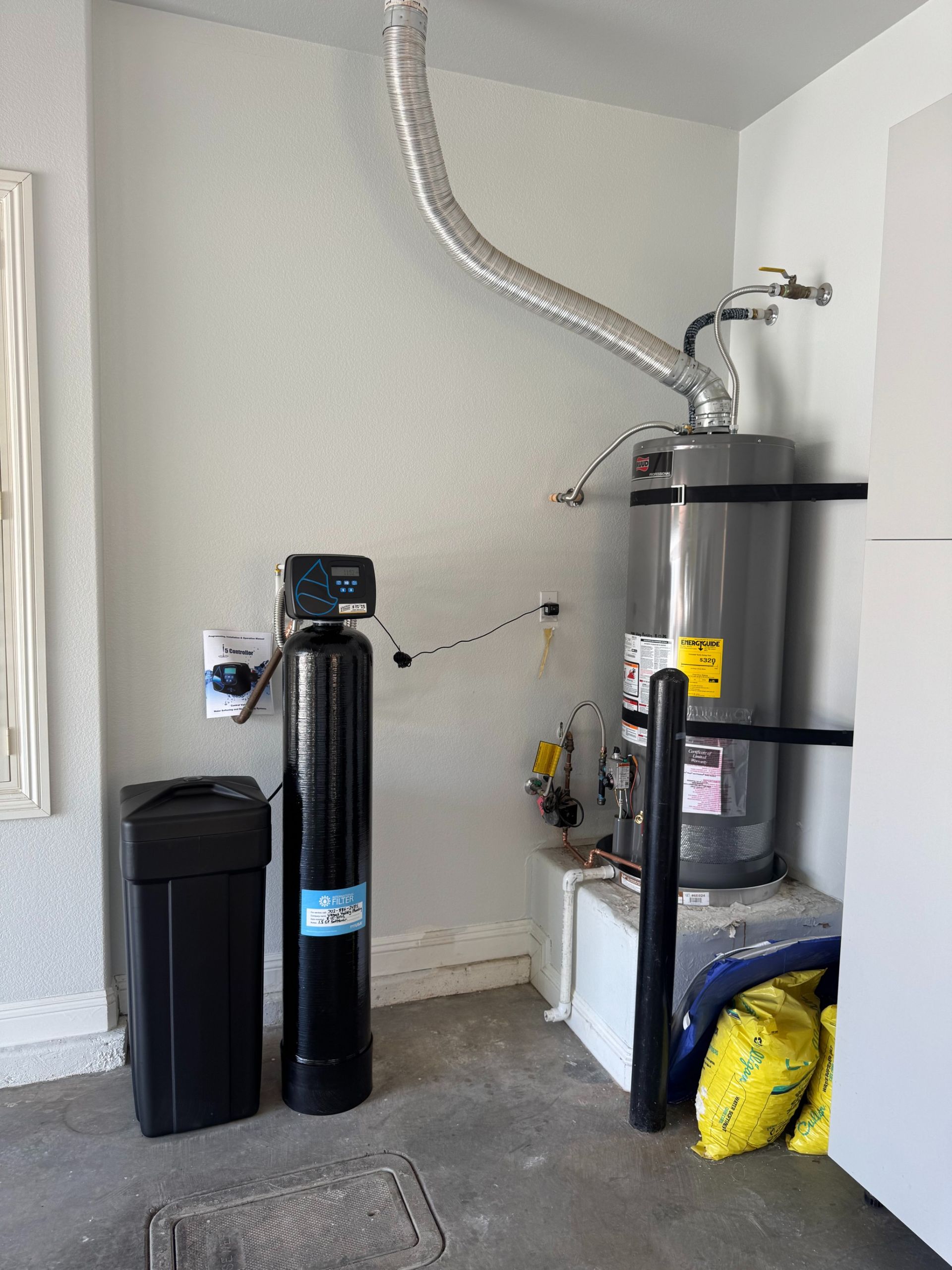 Laundry/utility room with water heater, black filter units, and exposed vent ducting along the wall.