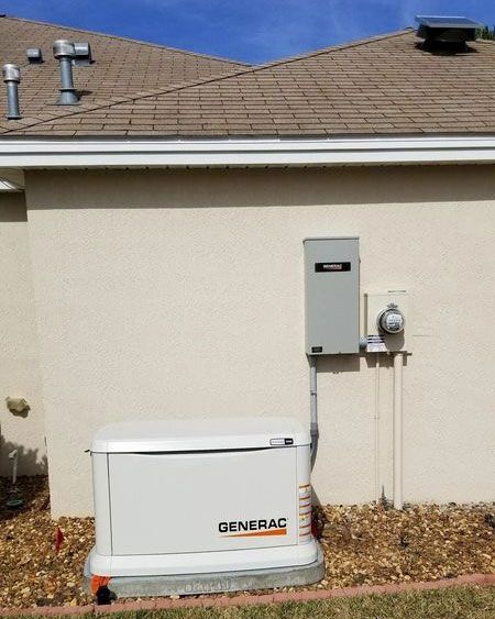 Generac home backup generator beside an electrical panel on a house exterior wall