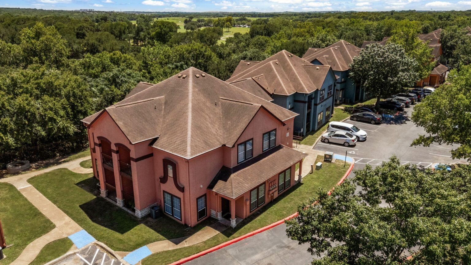 Aerial view of red and blue townhouses beside a parking lot and trees