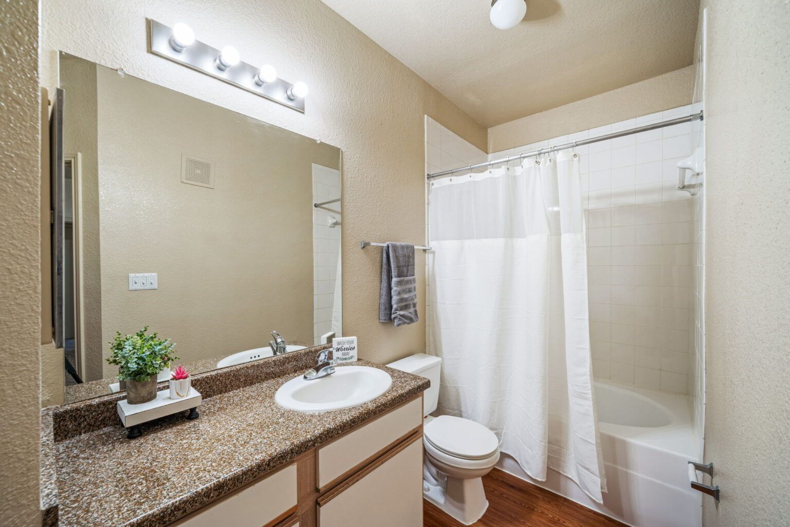 Bathroom with vanity mirror, sink, toilet, and shower with white curtain.